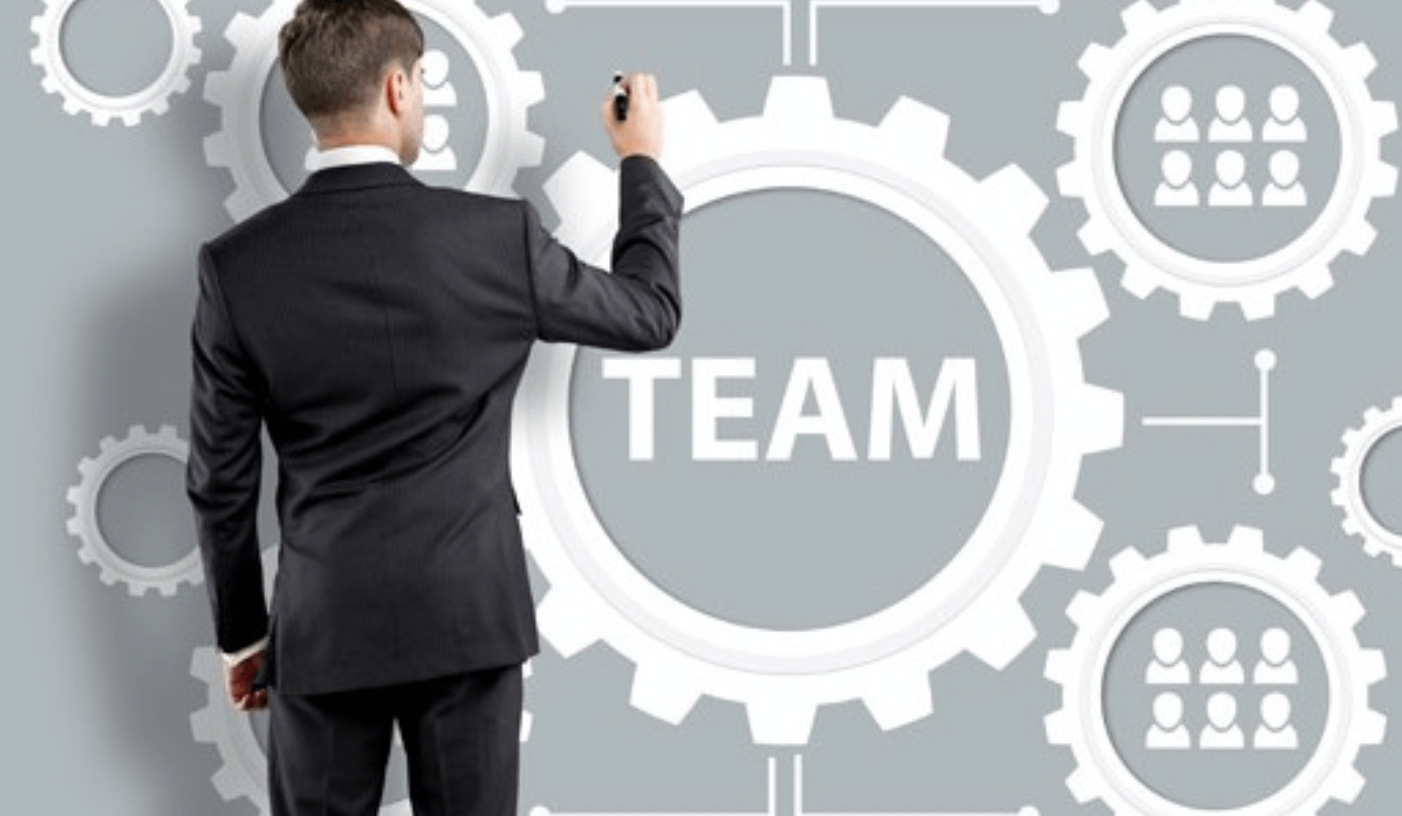 Formazione manageriale: uomo in giacca che scrive TEAM su ingranaggio. Risorse umane e direzione aziendale.
