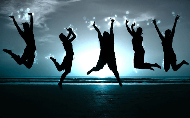 Silhouette di persone felici che saltano sulla spiaggia. Vivere felici facendo ciò che piace.
